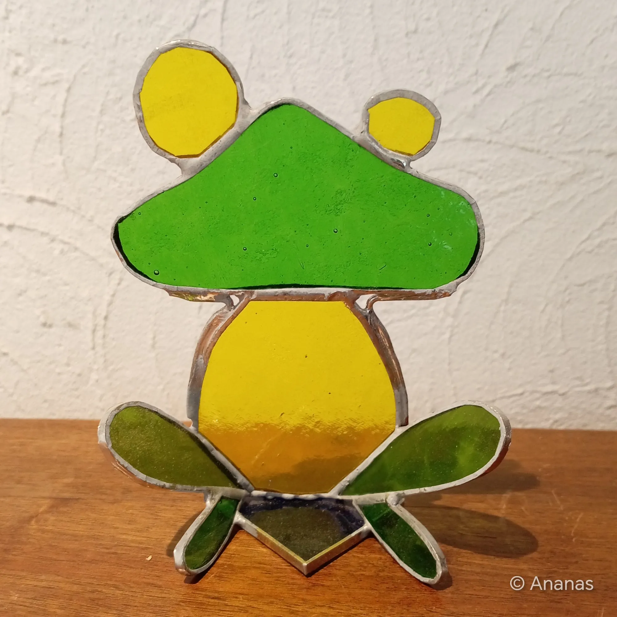 Une grenouille en vitrail qui semble prête à bondir, capturée dans un jeu de couleurs vives et de transparences.
